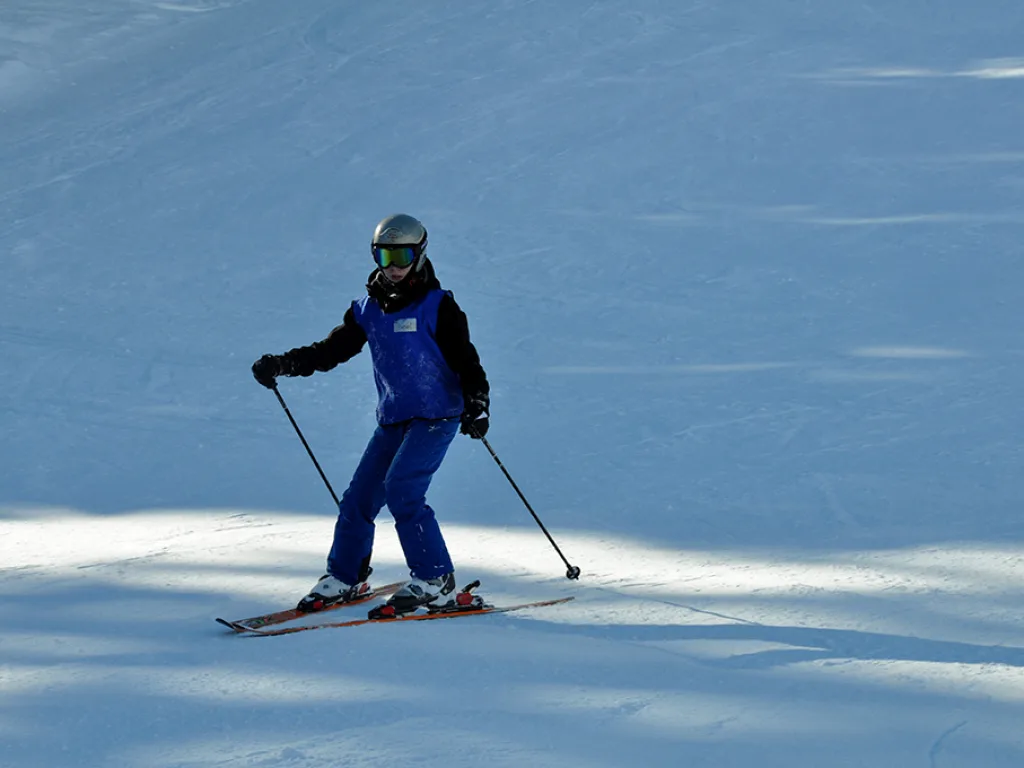 Skifahrer steht mit ausgebreiteten Armen auf der Piste.
